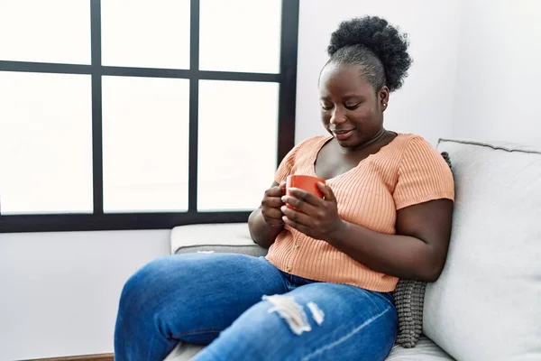年轻的非洲裔美国女人坐在沙发上喝咖啡 — 图库照片