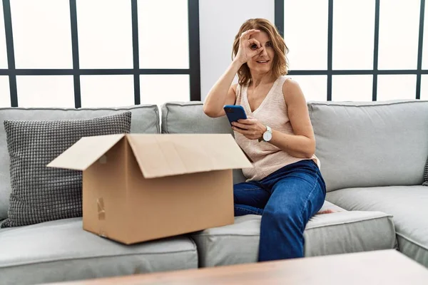 Mujer Mediana Edad Sentada Sofá Comprobando Paquete Entrega Teléfono Sonriendo —  Fotos de Stock