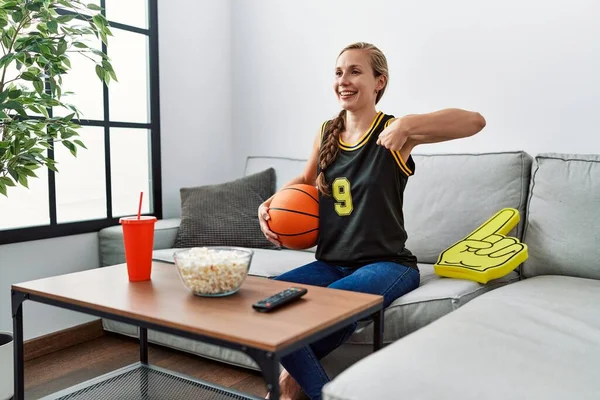 Joven Mujer Rubia Sosteniendo Pelota Baloncesto Animando Juego Señalando Dedo —  Fotos de Stock