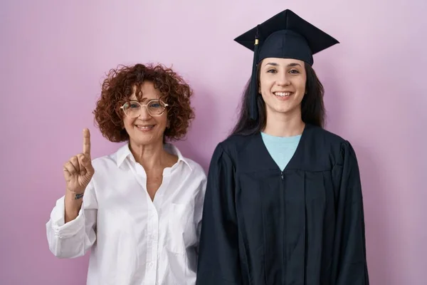 Hispanic Mother Daughter Wearing Graduation Cap Ceremony Robe Showing Pointing — Stok fotoğraf
