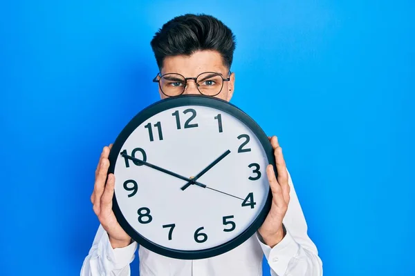 Young Hispanic Man Holding Big Clock Face Clueless Confused Expression — Stockfoto