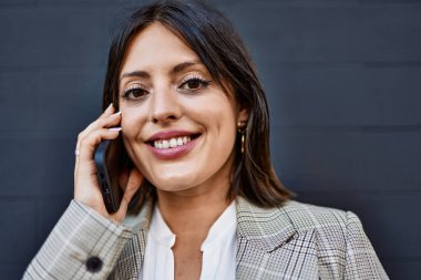 Genç İspanyol iş kadını gülümsüyor. Şehirdeki akıllı telefondan mutlu bir şekilde konuşuyor..