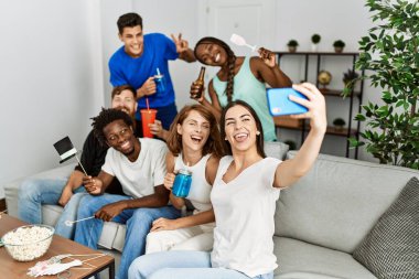 Bir grup genç arkadaş evdeki akıllı telefondan komik aksesuarlar kullanarak selfie çekiyorlar..