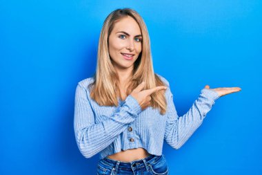 Gündelik giysiler giyen genç beyaz kadın kameraya hayret ediyor ve gülümsüyor.. 