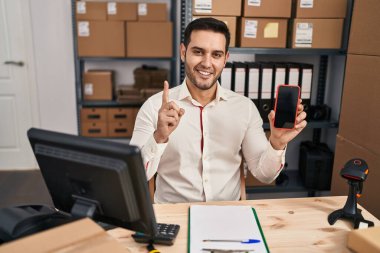 Sakallı genç İspanyol bir adam, küçük bir iş yerinde çalışıyor. Akıllı telefon ekranında gülümsüyor. Bir fikir ya da soruyla gülümsüyor. 