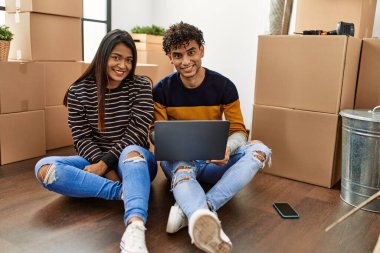 Genç Latin çift yeni evlerinde dizüstü bilgisayar kullanıyor..