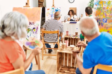 Bir grup orta yaşlı öğrenci resim stüdyosunda resim dersi alıyor..
