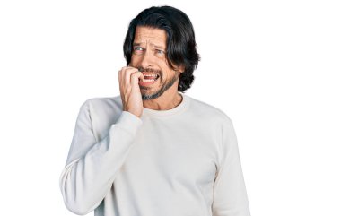 Orta yaşlı, günlük kıyafetler giyen, gergin ve elleri ağızda çivi yiyen beyaz bir adam. anksiyete. 