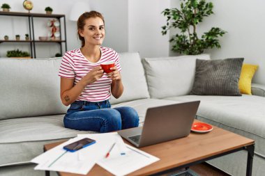 Kahve içen genç bir kadın evde çalışıyor.