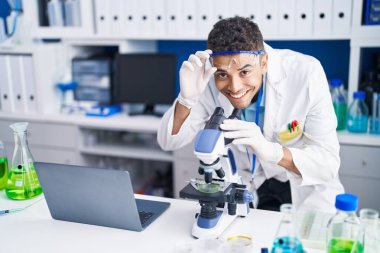 Laboratuvarda mikroskop kullanan Afrikalı Amerikalı bilim adamı.