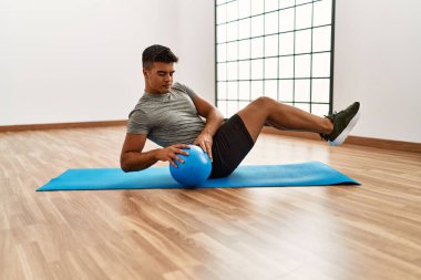 Spor merkezinde top kullanarak karın kaslarını çalıştıran genç bir İspanyol.