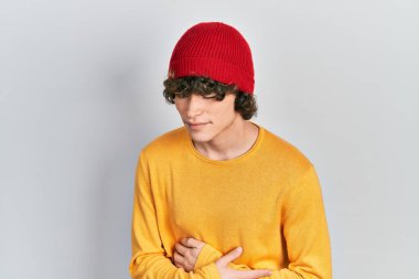 Mide bulantısı, acı verici bir hastalık yüzünden eli karnında yün şapka takan yakışıklı bir genç. Ağrı kavramı. 