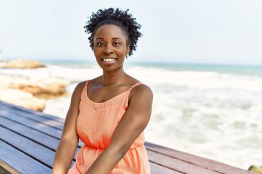 Genç Afrikalı Amerikalı bir kadın kumsalda mutlu bir yaz günü gülümsüyor.