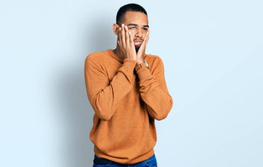 Genç Afro-Amerikan adam günlük kıyafetler giyiyor. Yorgun eller, yüzünü kapatıyor. Depresyon ve üzüntü yaşıyor. 
