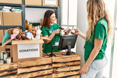 İki gönüllü kadın, hayır kurumunda çalışmaktan mutlu gülümsüyor..