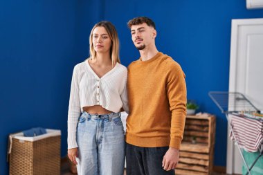 Genç adam ve kadın sırıtan bir çift çamaşırhanede birbirlerine sarılıyorlar.