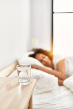 Orta yaşlı İspanyol kadın yatak odasında yatakta uyuyor.