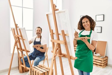 Resim stüdyosunda gülümseyen iki orta yaşlı öğrenci..