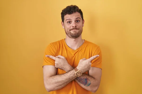 Homem Hispânico Jovem Sobre Fundo Amarelo Apontando Para Ambos Lados — Fotografia de Stock