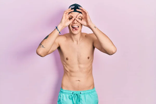 Young Hispanic Man Wearing Swimwear Swimmer Glasses Doing Gesture Binoculars — ストック写真