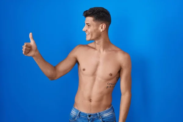 Joven Hombre Hispano Pie Sin Camisa Sobre Fondo Azul Mirando —  Fotos de Stock