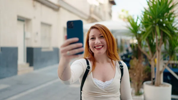 若いです赤毛女性笑顔自信を持って作ります自画撮りによってスマートフォンでストリート — ストック写真