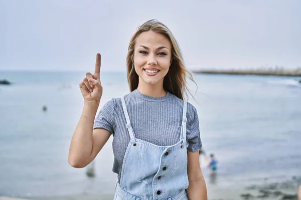 Young Caucasian Woman Outdoors Showing Pointing Finger Number One While — Stockfoto