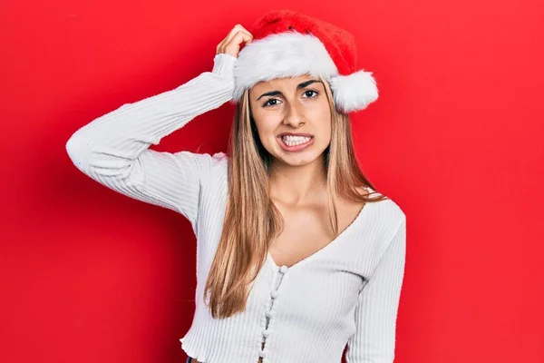 クリスマスの帽子を身に着けている美しいヒスパニック系の女性は混乱し 質問について不思議 疑いもなく頭に手を置いて考える 包括的な概念は — ストック写真