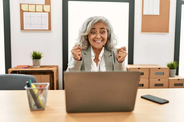 中年女商人坐在办公桌前 在办公室使用笔记本电脑 兴奋地举起双臂 眼睛闭上 笑着庆祝胜利 获奖者概念 — 图库照片