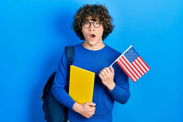 Guapo Joven Estudiante Intercambio Sosteniendo Bandera Asustado Sorprendido Con Sorpresa — Foto de Stock