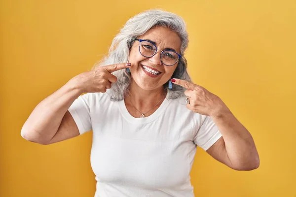 中年妇女 头发灰白 站在黄色的背景上 笑容满面 用手指 牙齿和嘴指尖 牙齿健康概念 — 图库照片