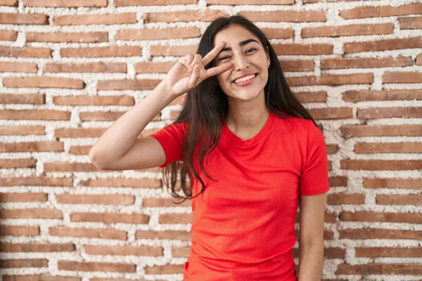 Tuğla Duvarın Üzerinde Duran Genç Kız Barış Sembolü Yapıyor Yüzünde — Stok fotoğraf