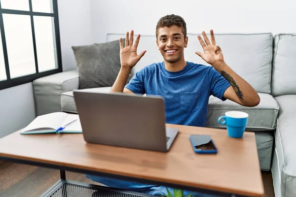自信と幸せ笑顔ながら 若いですハンサムなヒスパニック系の男を使用してノートパソコンを床に座って表示し 指数9で指摘します — ストック写真