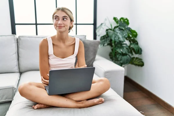 Genç Sarışın Kadın Evinde Dizüstü Bilgisayar Kullanıyor Kanepeye Oturmuş Gülümsüyor — Stok fotoğraf