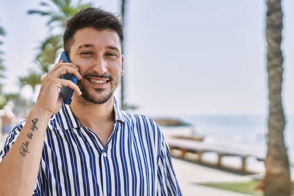 Young handsome man talking to the phone by the sea