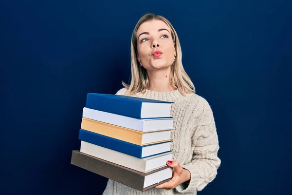 stock image Beautiful caucasian woman holding a pile of books looking at the camera blowing a kiss being lovely and sexy. love expression. 