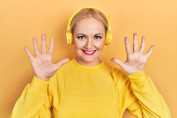 Young Blonde Woman Listening Music Using Headphones Showing Pointing Fingers — ストック写真