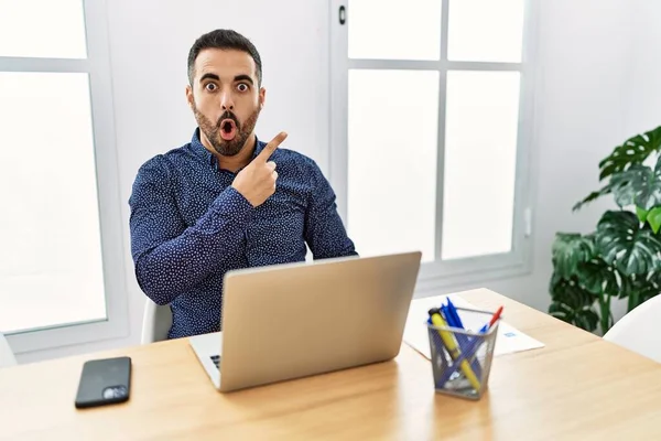 Young Hispanic Man Beard Working Office Laptop Surprised Pointing Finger — ストック写真