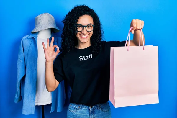 Young Hispanic Woman Curly Hair Wearing Staff Shirt Holding Shopping —  Fotos de Stock