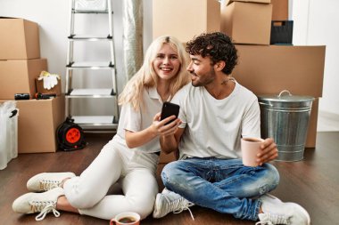 Genç ve güzel bir çift dizüstü bilgisayar kullanıyor. Yeni evinde kahve içiyor..