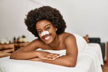 Genç Afrikalı Amerikalı kadın güzellik merkezinde kendine güvenen burun bandı takıyor.