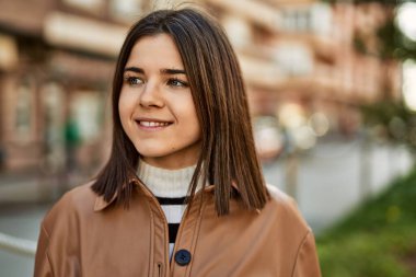 Genç, güzel, esmer kadın dışarıda mutlu bir şekilde gülümsüyor.