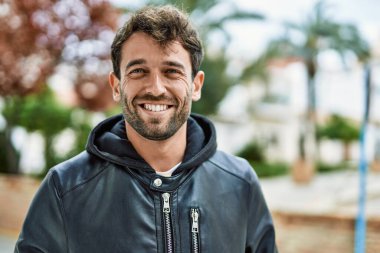 Yakışıklı, sakallı, açık havada mutlu gülümseyen bir İspanyol.