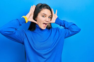 Balıkçı yaka kazak giyen genç esmer kız, gülümseyen, gülümseyen, elleri havada dikizcilik yapan. Şaşırdım ve çıktım. 