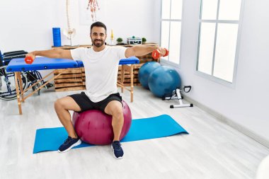 Genç İspanyol hasta, rehabilitasyon seansında sağlıklı top ve dambıllarla gülümsüyor.