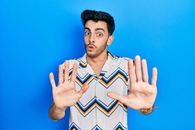 Latin asıllı genç bir adam, sıradan kıyafetler giyip avuçlarını hareket ettiriyor. Korkmuş ve iğrenç bir ifadeyle reddediyor. Dur ve yasakla. 