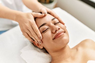 Genç Latin kadın güzellik merkezinde yüz masajı yaptırırken rahatlamış.