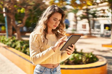 Parkta dokunmatik ped kullanan genç bir kadın.