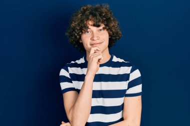 Sıradan çizgili tişört giyen yakışıklı genç adam kameraya kendinden emin bakıyor kolları çapraz ve çenesi açık gülümsüyor. Olumlu düşünmek. 