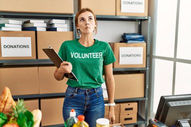 Bağışta gönüllü tişört giyen genç esmer kadın dudağıyla balık suratı yapıyor, çılgınca ve komik bir jest. Komik ifade. 